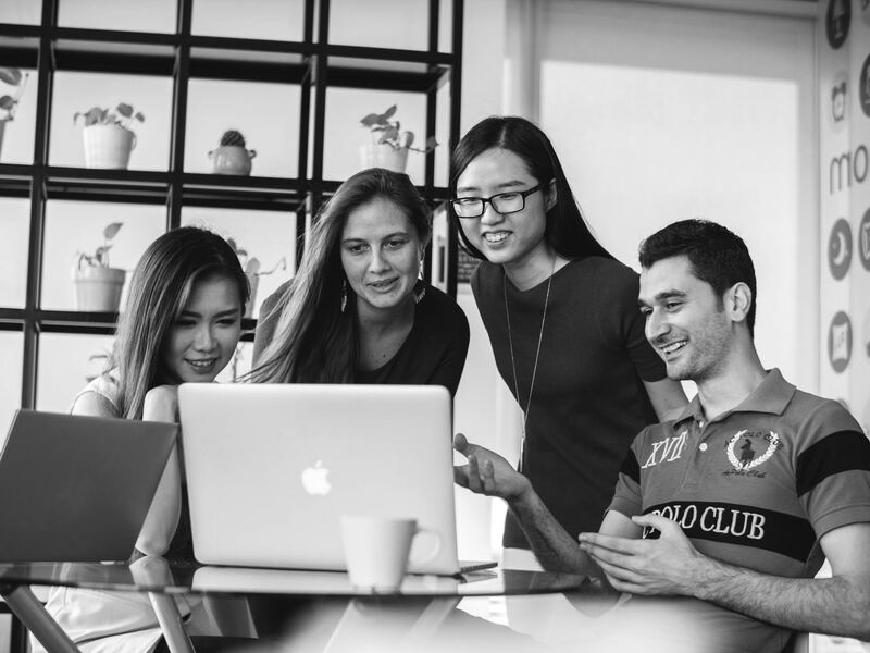 Spark Consulting team members gathered around a laptop, smiling as they plan a campaign