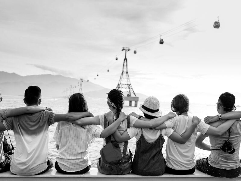 A row of friends with arms around each other looking out over the hills together
